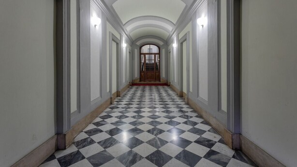 A long hallway with a checkered marble floor, white walls, and a wooden door at the end. - Turin Central Loft Carignano by Wonderful Italy (Torino)