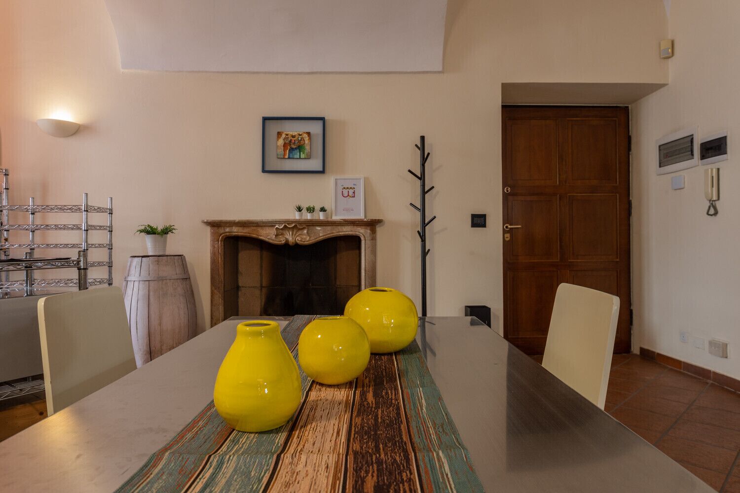 A dining area with a long table, chairs, and yellow vases.