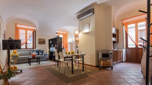 A living room with a sofa, dining table, chairs, and a TV. There is a kitchen area with a microwave and cabinets. - Turin Central Loft Carignano by Wonderful Italy (Torino)
