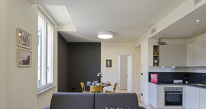 A modern apartment with a grey sofa, a dining area, and a kitchen. - Riviera Flavour Apartments by Wonderful Italy - Lavanda (Santa Margherita Ligure)