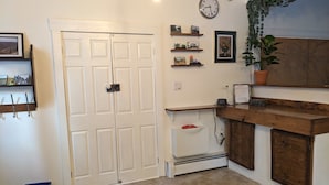 Una cocina con dos puertas blancas, horno empotrado y encimera de madera. Se observan estantes con adornos y un reloj en la pared.