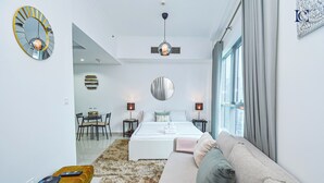 A modern bedroom with a bed, bedside tables, a sofa, and a dining area. - Brand New Studio with Marina View -PAU (Dubai)
