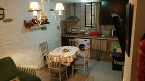 Une cuisine compacte comprenant une table à manger, des chaises, un lave-linge et un téléviseur.