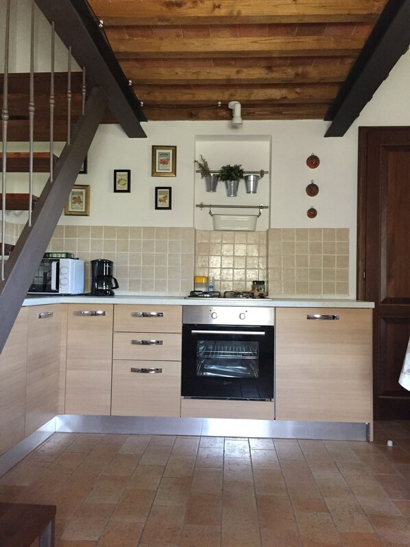 A kitchen with wooden cabinets, a built-in oven, and a tiled backsplash. - Villa Le Ripe (Gambassi Terme)