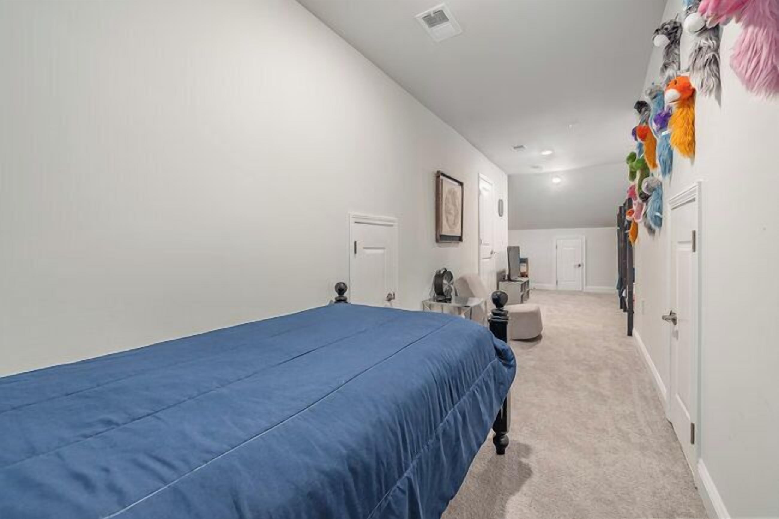 A bedroom with a single bed, a desk, a chair, a small table, and a wardrobe.