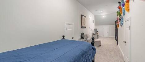 A bedroom with a single bed, a desk, a chair, a small table, and a wardrobe.