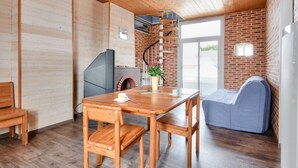 A cozy kitchen with a wooden table, chairs, a brick wall, and a spiral staircase.