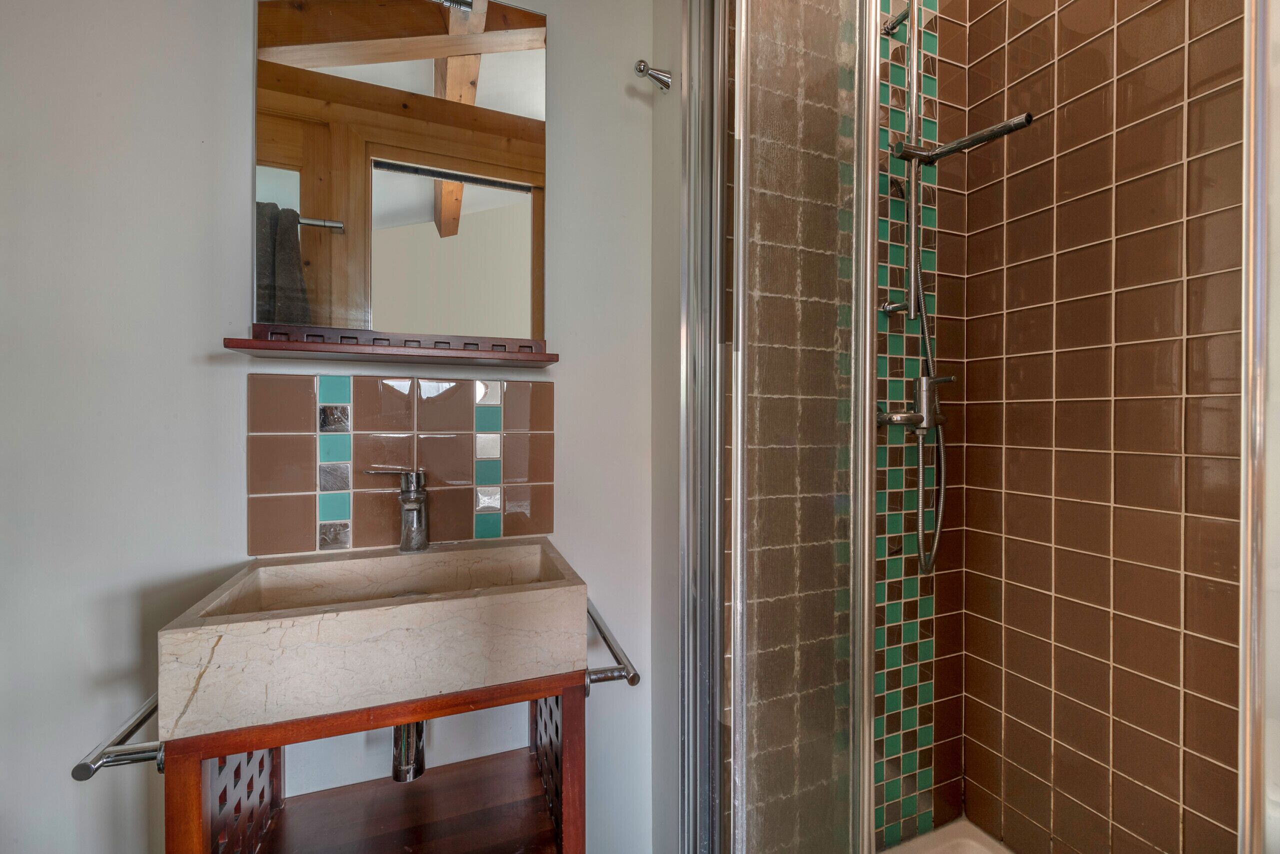 Une salle de bain équipée d’un lavabo, d’un miroir et d’un espace douche.