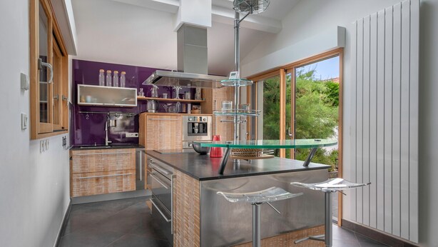 A modern kitchen with a central island, built-in appliances, and a large window offering a view of greenery. - Seafront villa for 10 adults and 1 child (Préfailles)