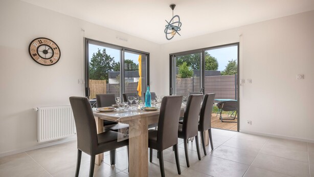 A dining area with a wooden table, six chairs, and a large window. - Tour-du Parc - Modern house for 8 (Le Tour-du-Parc)