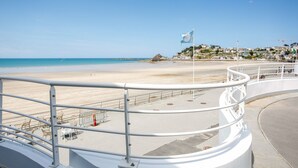 A beach with a white railing, clear sky, and buildings in the background. - Holiday with sea view in Pléneuf-Val-André (Pléneuf-Val-André)