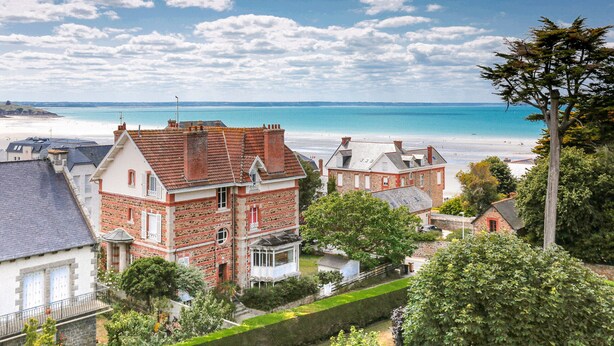 A coastal town with a prominent red brick building with a balcony, surrounded by greenery and a view of the beach and sea. - Holiday with sea view in Pléneuf-Val-André (Pléneuf-Val-André)