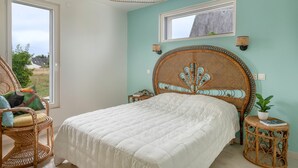 Un dormitorio con una cama grande, muebles de mimbre, una ventana y vistas al exterior.