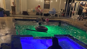 A swimming pool with a person in the water, surrounded by a patio area with chairs and tables. - Private Pool, Gazebo, Firepit, and Hot Tub. Optional Guest Suite (Lake Worth)