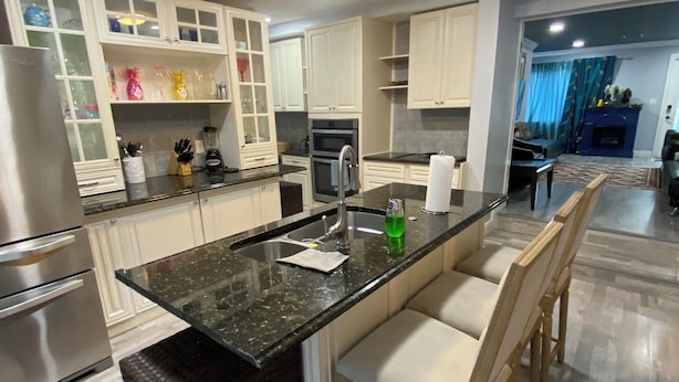 A modern kitchen with a central island, stainless steel appliances, and white cabinetry. - Private Pool, Gazebo, Firepit, and Hot Tub. Optional Guest Suite (Lake Worth)