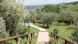 A pathway leading through a garden with various trees and a view of distant hills. - Villa Le Ripe Apartments (Gambassi Terme)