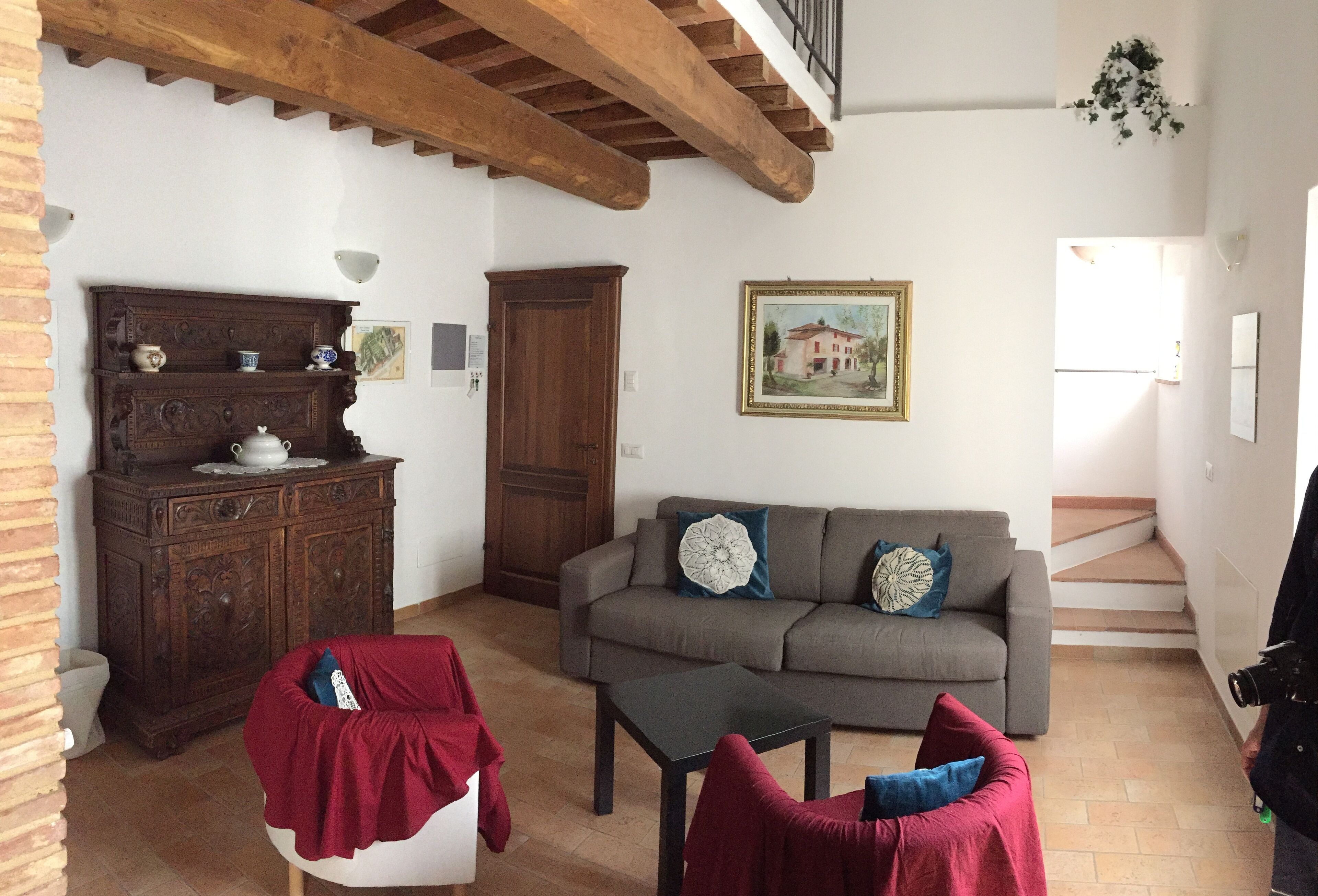 Una sala de estar con un sofá, una mesa de centro, un aparador de madera y una escalera que conduce a un nivel superior.