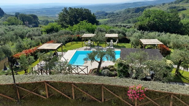 A pool surrounded by lush greenery and a view of distant hills. - Villa Le Ripe Apartments (Gambassi Terme)
