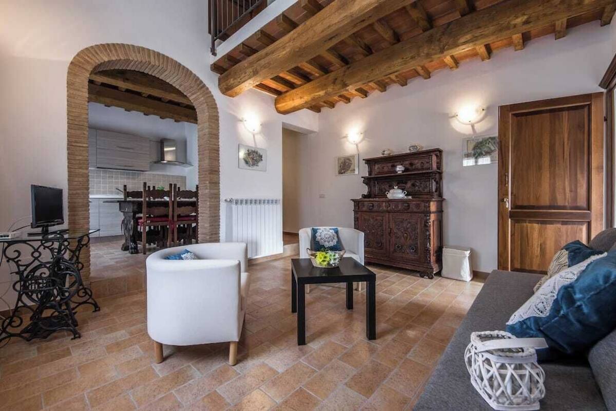 A spacious living area with a high ceiling, a fireplace, a dining area, and a kitchen visible through an archway.