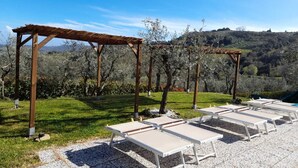 A garden with pergolas and sun loungers. - Villa Le Ripe Apartments (Gambassi Terme)
