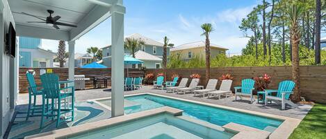 A swimming pool with multiple lounge chairs and a ceiling fan.