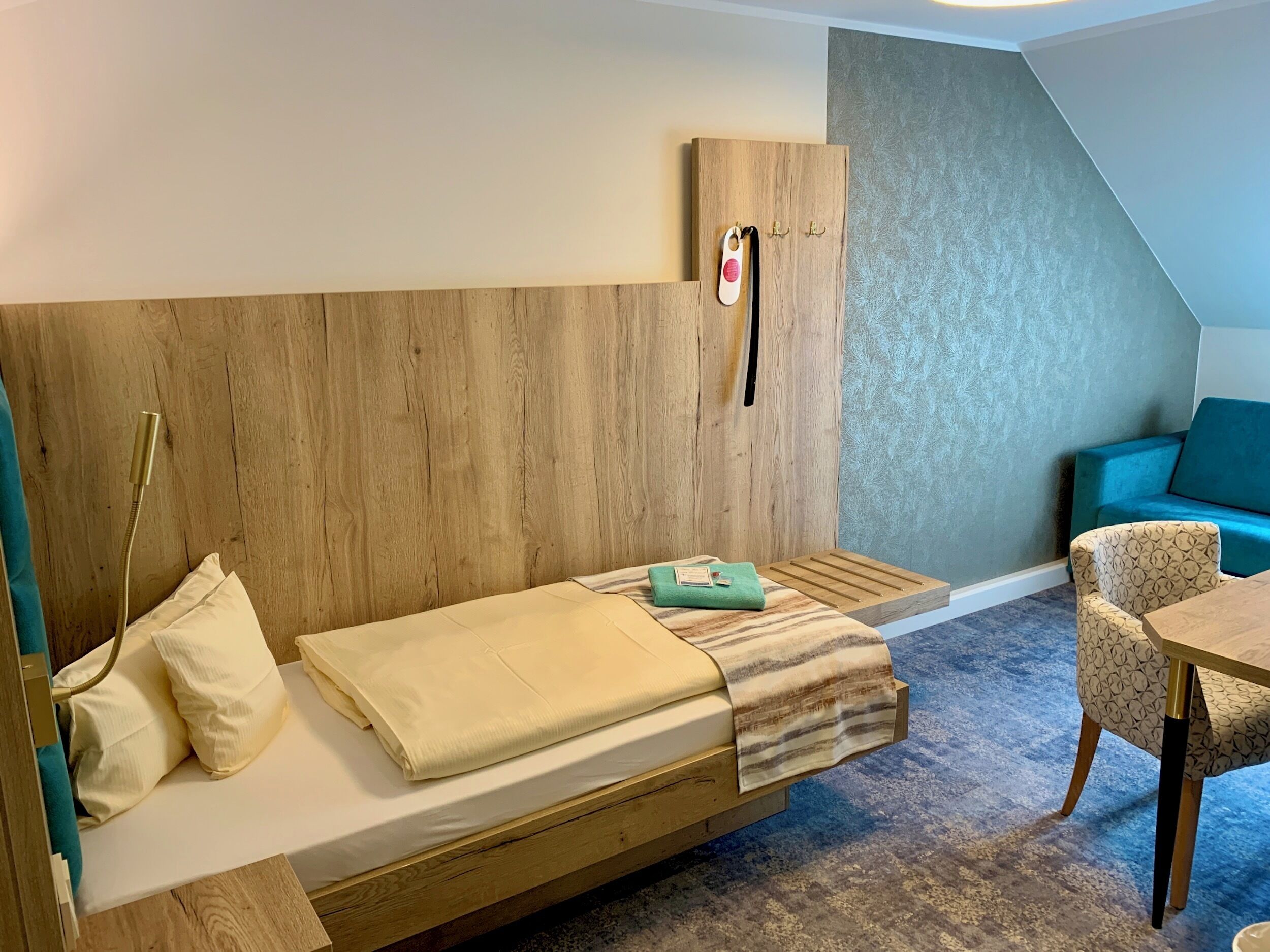 Ein kleines Zimmer mit einem Holzbett, einem kleinen Tisch und einem blauen Sofa.