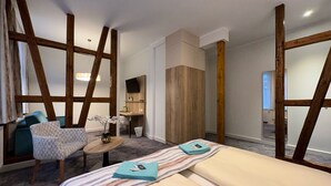Una habitación de hotel con una cama, una silla, una mesita y un televisor.