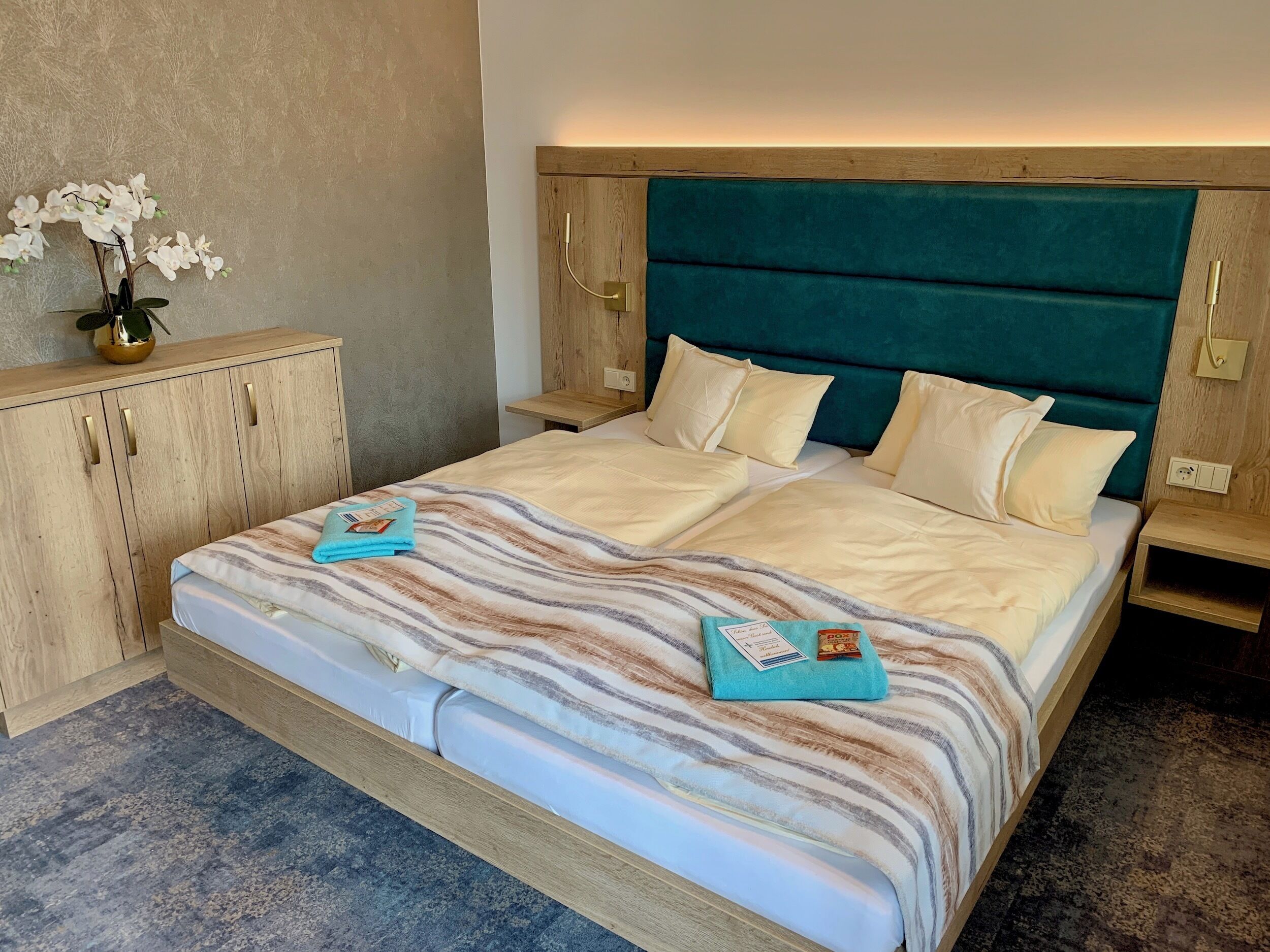 Una habitación de hotel con una cama grande, cabecero de madera y una mesita de noche con lámpara.
