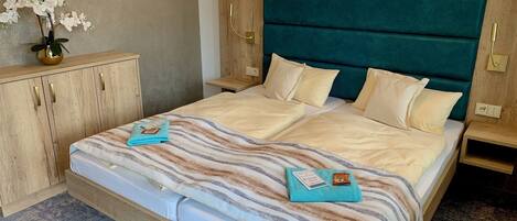 Una habitación de hotel con una cama grande, cabecero de madera y una mesita de noche con lámpara.
