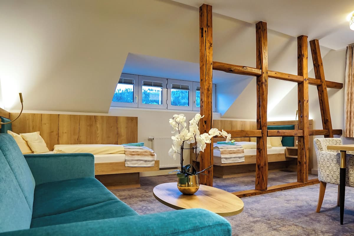 Una habitación acogedora con techo de madera, un sofá, una mesita con un jarrón y una ventana con vistas a árboles.