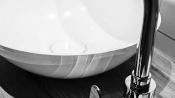 Un lavamanos moderno con un grifo cromado elegante y un lavabo redondo blanco.