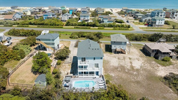 Un quartier résidentiel avec des maisons, une piscine et une plage en arrière-plan.