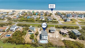 Une vue aérienne d’un quartier résidentiel avec des maisons, des routes et une plage en arrière-plan.