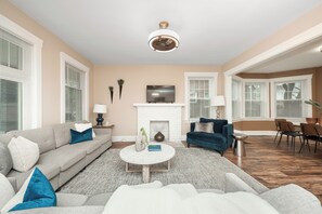 A living room with a fireplace, a sofa, a coffee table, and a TV. - All for One, One for All- Suite 2B (Cincinnati)