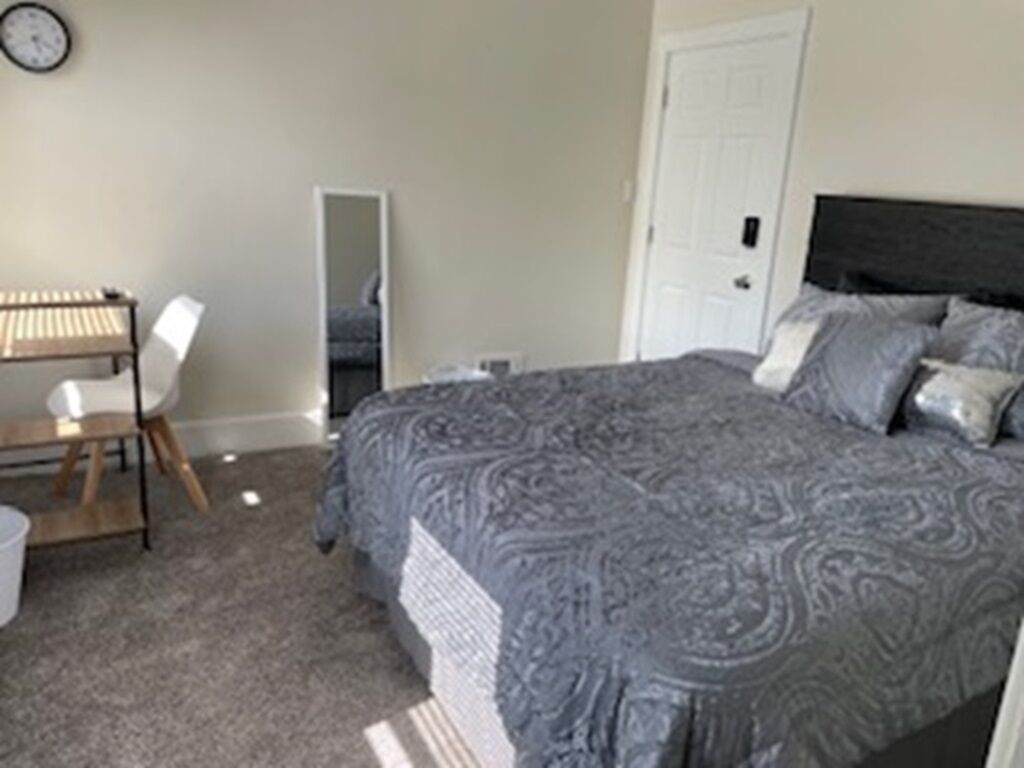 Een slaapkamer met een groot bed, een bureau en een stoel.