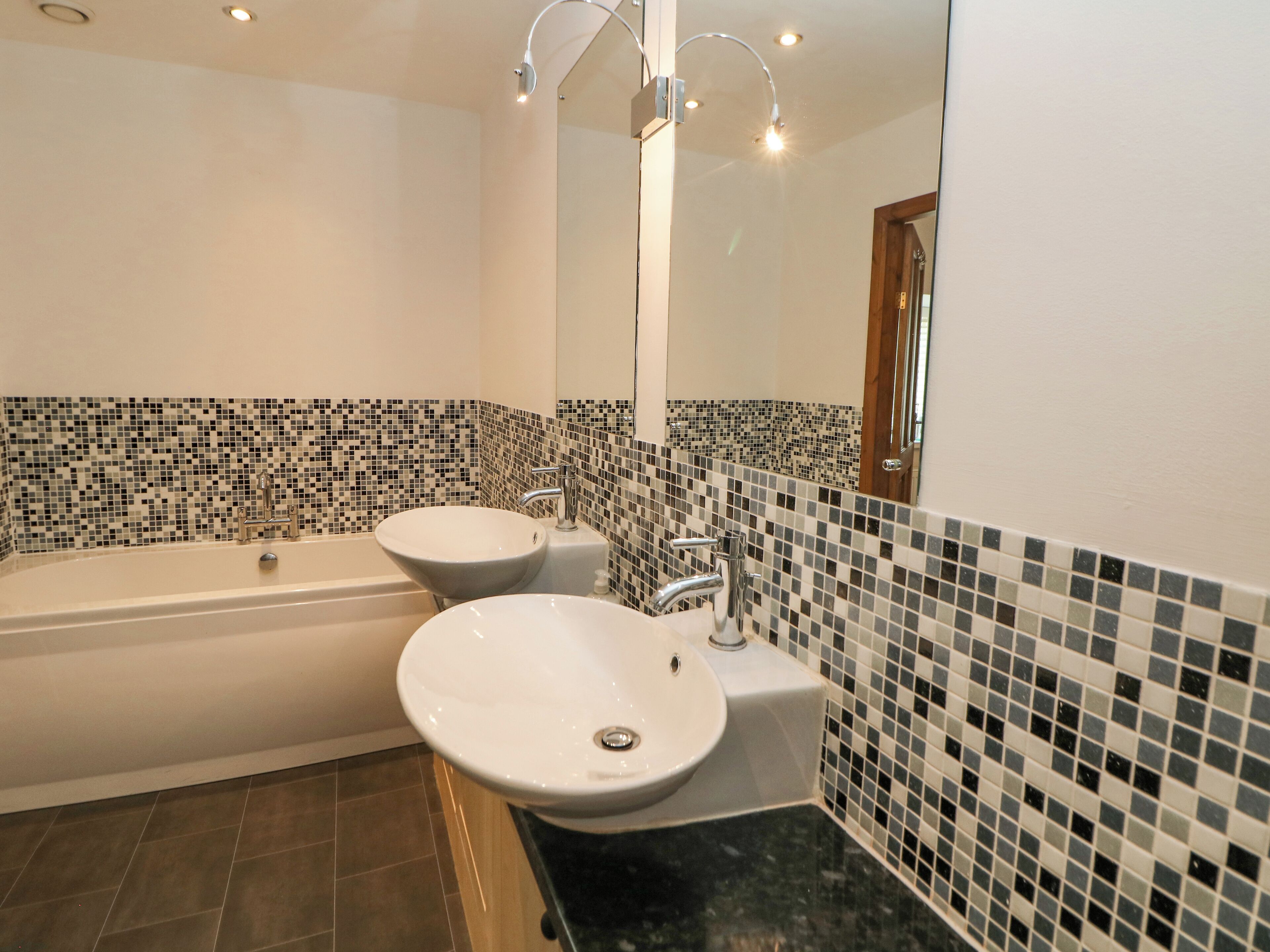 A bathroom with a bathtub, two sinks, and a tiled backsplash.