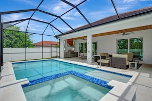 A covered swimming pool with a clear view of the surrounding area, including a patio with outdoor furniture and a view of the neighborhood. - Naples Coastal Retreat: Heated Pool, Hot Tub, (Naples)