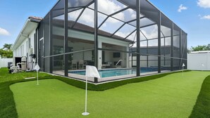 Ett modernt hus med en stor glasveranda, en swimmingpool och en välskött gräsmatta.