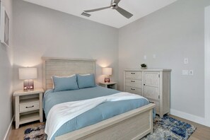 A bedroom with a bed, nightstands, a dresser, and a ceiling fan.