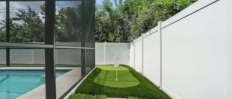 A modern outdoor pool area with a clear view of the sky and surrounding greenery.
