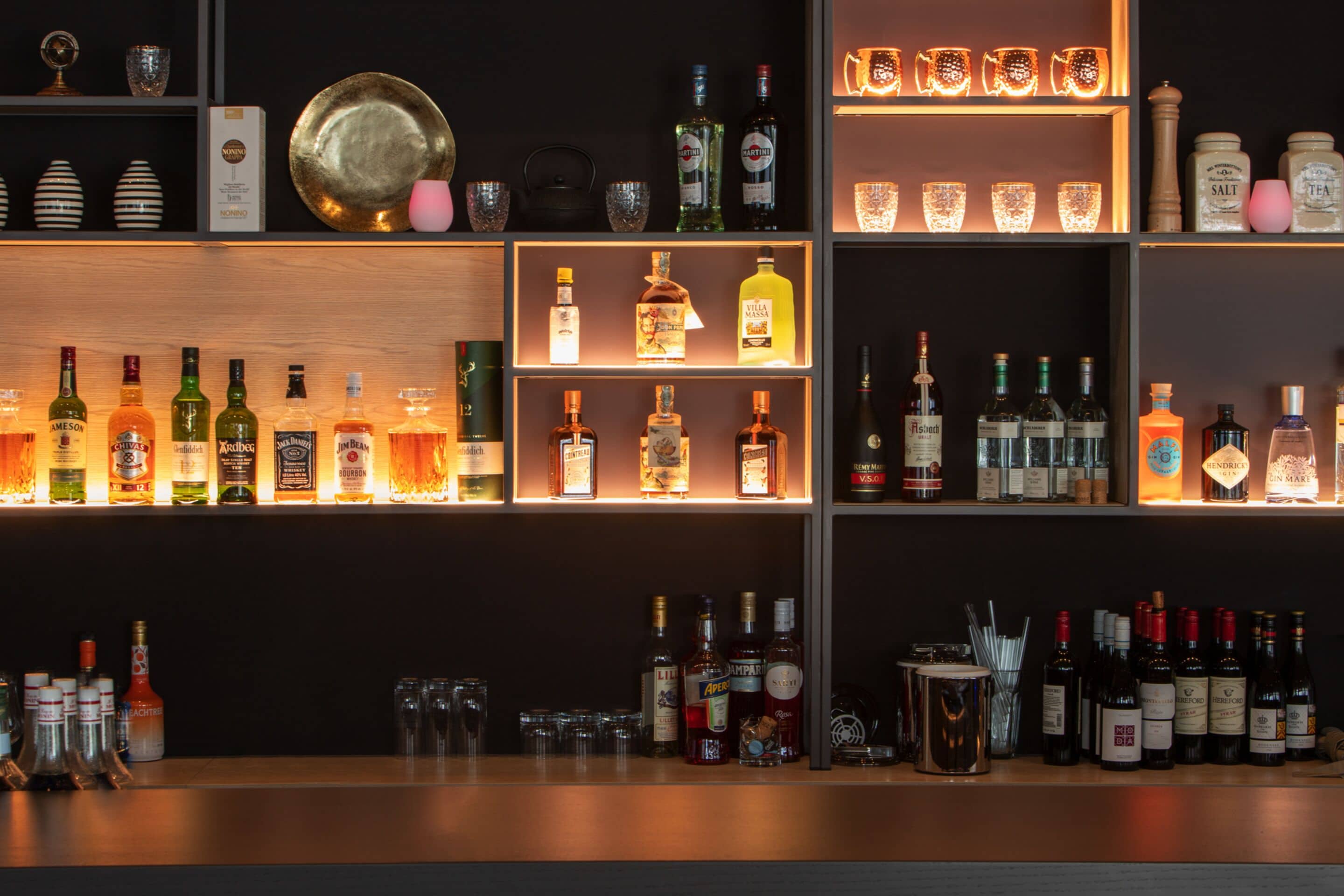 A bar area with shelves of various liquor bottles and glasses.