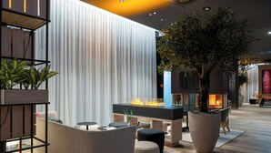 Un'area lounge moderna con un elemento a fuoco, posti a sedere e un'ampia pianta in vaso.