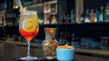 Une table de bar avec un verre à cocktail, un bocal de collations et un bol de noix.
