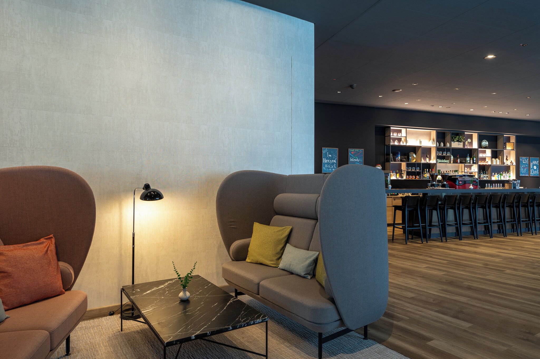 A modern lounge area with sofas, a coffee table, and a bar with stools.