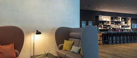 A modern lounge area with sofas, a coffee table, and a bar with stools.