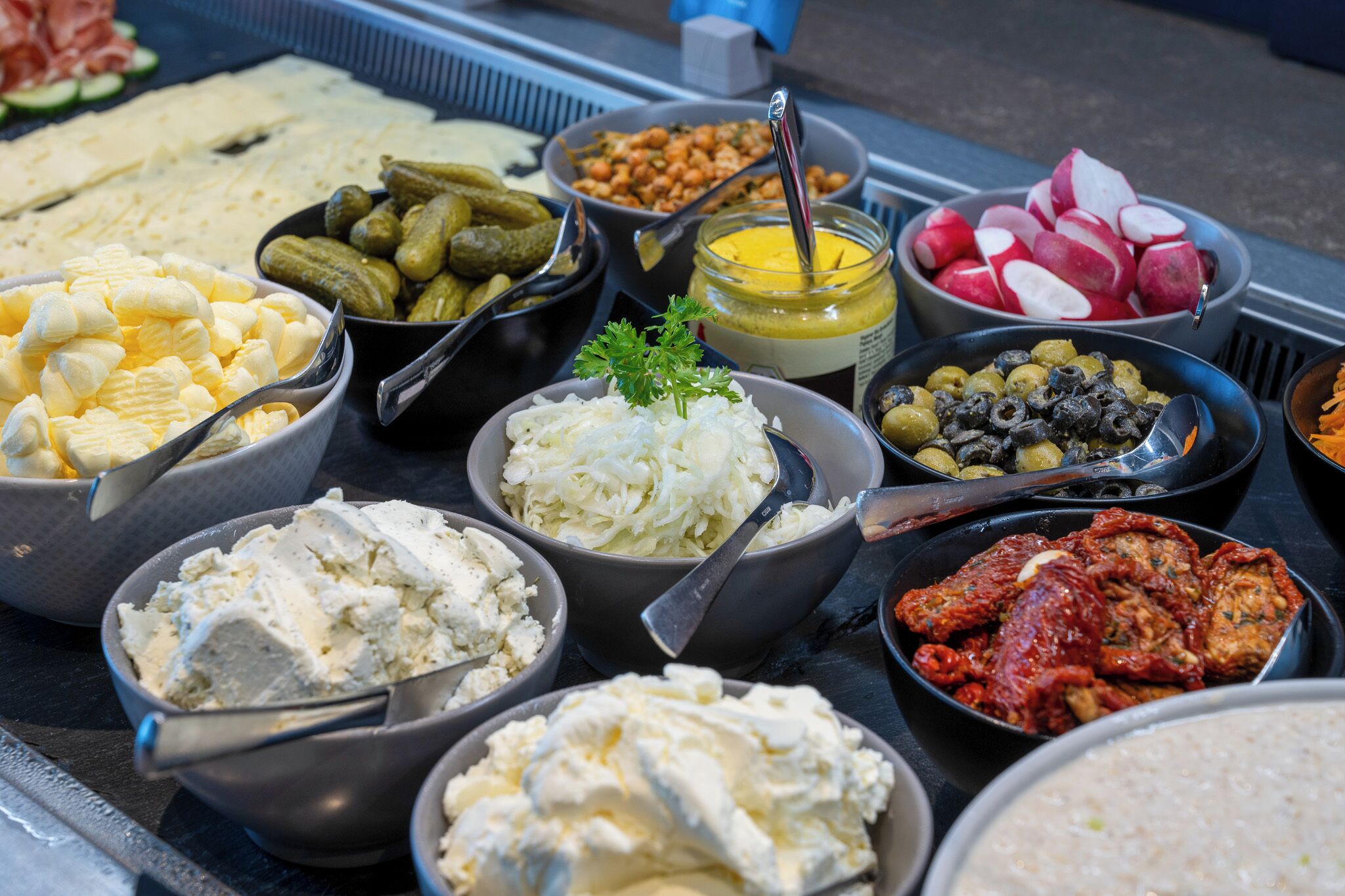 Diversos productos alimenticios, como quesos, pepinillos, aceitunas y salsas.