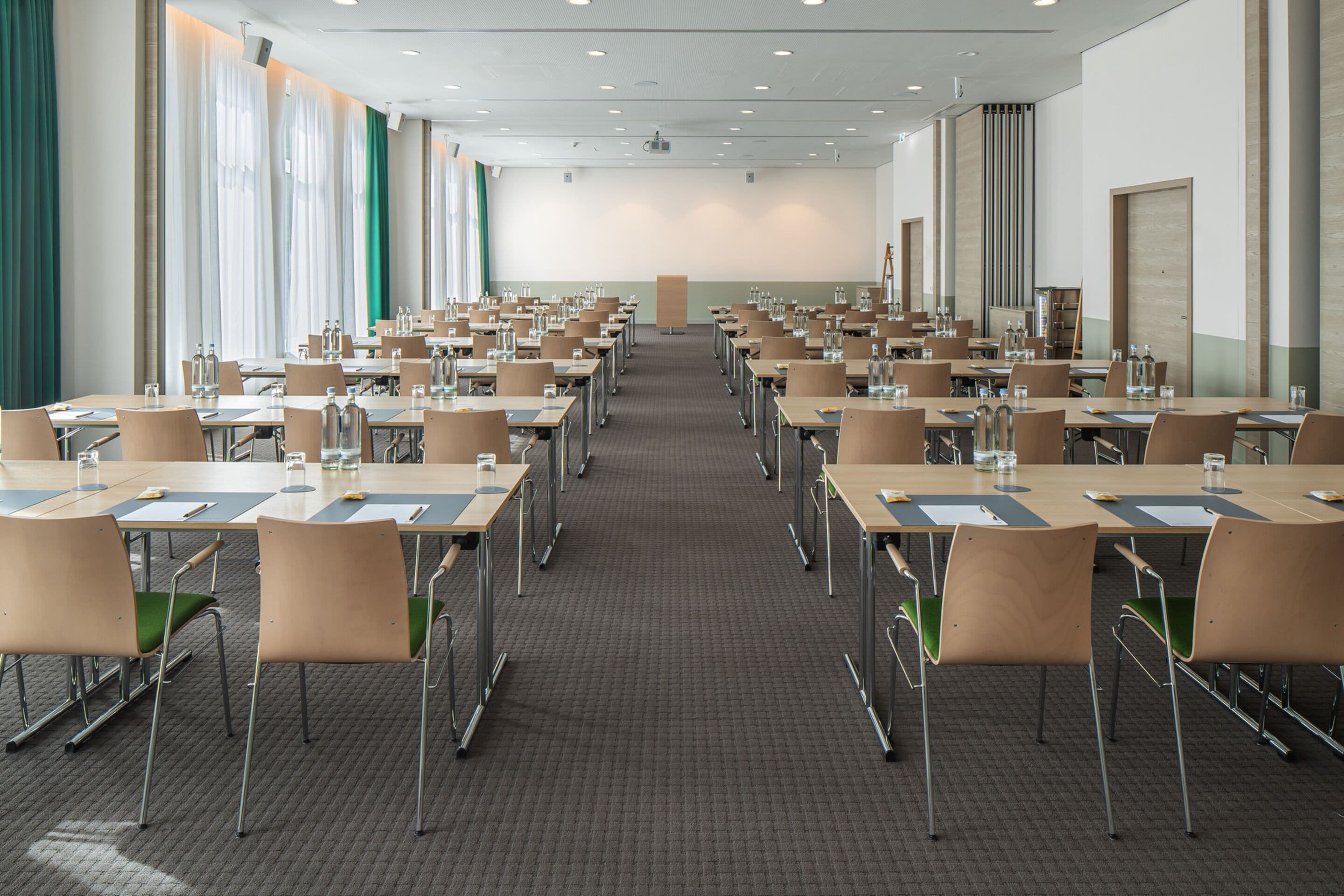 A conference room with multiple tables and chairs, arranged in rows.