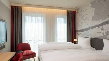 Une chambre d’hôtel avec un lit, un bureau, une chaise et une carte accrochée au mur.