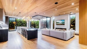 A modern interior with a wooden ceiling, a dining area, a sofa, and a fireplace.