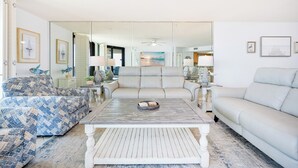 Un salon avec un canapé, une table basse et un grand miroir.